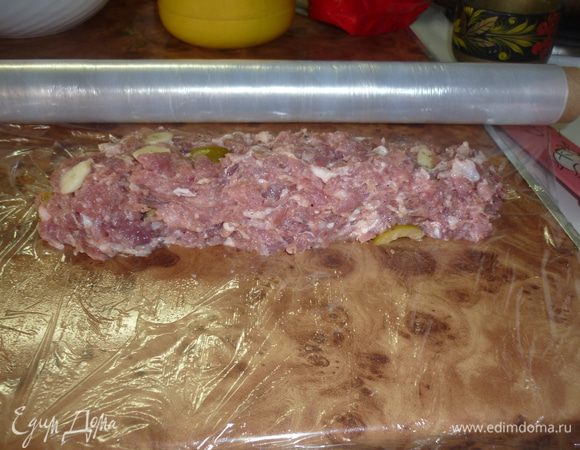 на стол расстелить пищевую пленку. я не отрезала, а отмотала от рулона. выложить на нее половину фарша, распределить полоской, оставив от краев сантиметров по 5