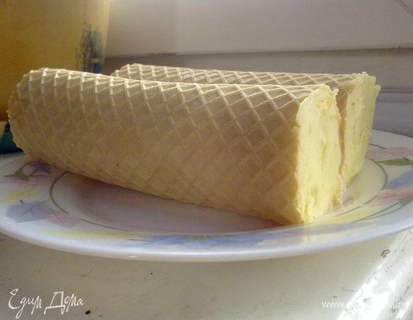 Нанести картофель тонким слоем на вафельный корж, положить целую сосиску, свернуть рулет.