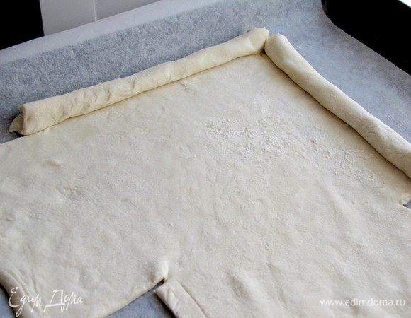 Раскатать тесто в прямоугольный пласт, размером 20х30 см. Противень накрыть смазанным маслом листом пергамента. Положить на него тесто, подровнять края. С каждого угла вырезать квадрат размером 10х10 см. Свернуть края в аккуратные бортики. У меня было две пластины слоеного теста в упаковке, поэтому получилось два маленьких пирога.