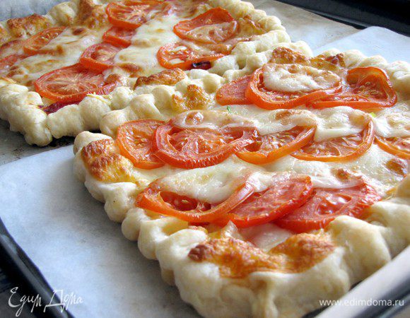 На них выложить по диагонали помидоры  и моцареллу. Поставить в духовку на 15 минут. Готовый пирог посолить, поперчить, украсить базиликом.