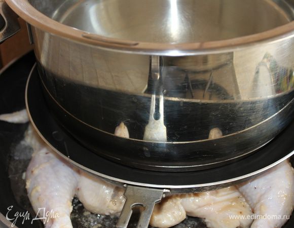 После маринования смахнуть с цыпленка остатки маринада (иначе будет гореть) и уложить его на сковороду. Сверху прикрыть другой сковородой с меньшим диаметром (можно и без нее) и поставить еще большую кастрюлю с водой (для утяжеления). Поскольку я готовила двух цыплят, мне пришлось жарить их сразу на двух сковородах с подобным сооружением одновременно. В это время необходимо включить духовой шкаф, чтобы он разогрелся до температуры 200 градусов