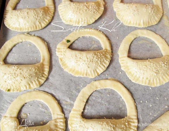 Пирожки смазать яйцом и посыпать кунжутом. Выпекать в духовке до готовности.