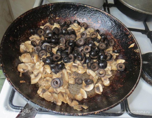 Грибы нарезать пластинками, пассеровать в оставшемся масле около 5 минут, посолив и поперчив. Маслины нарезать колечками и добавить к грибам. Тушить ещё 5-7 минут.