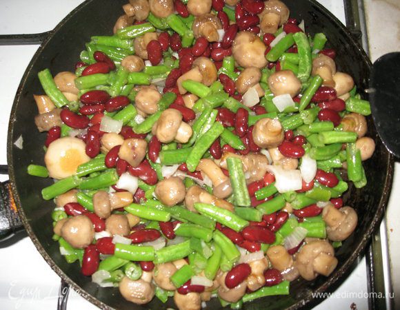После того как стручковая фасоль станет мягкой, открываем консервированную фасоль, высыпаем ее туда же, солим по вкусу, перемешиваем и тушим еще 3 мин. Добавляем зелень петрушки с рубленым чесноком, перемешиваем и еще тушим 2 мин.
