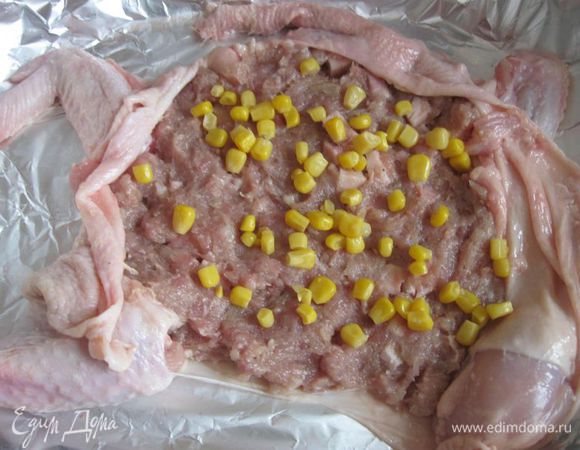 На кожу выложить слой фарша. Положить часть кукурузы.

