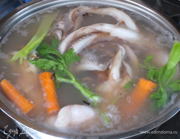 В глубокую кастрюлю налить воду, добавить овощи, лавровый лист, гвоздику, посолить, поставить на огонь. Довести до кипения,и, держа осьминога за голову, погрузить его щупальца 3-4 раза в воду (таким образом сохраняем целостность его кожи и мясо щупальцев будет нежнеe), затем  полностью опустить осьминога,уменьшить огонь и варить около 30-35 минут (20 минут на каждые 500 г осьминога). Осьминог должен остыть в этой же воде, в которой и варился.