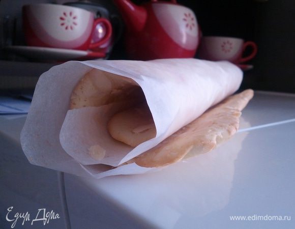 Пока корж горячий закрутить его в пергаментную бумагу и дать полностью остудиться. Тем временем готовим крем - сливки взбить с сахарной пудрой, можно добавит ванильную эссенцию. Мелко порезать клубнику и смешать все. 