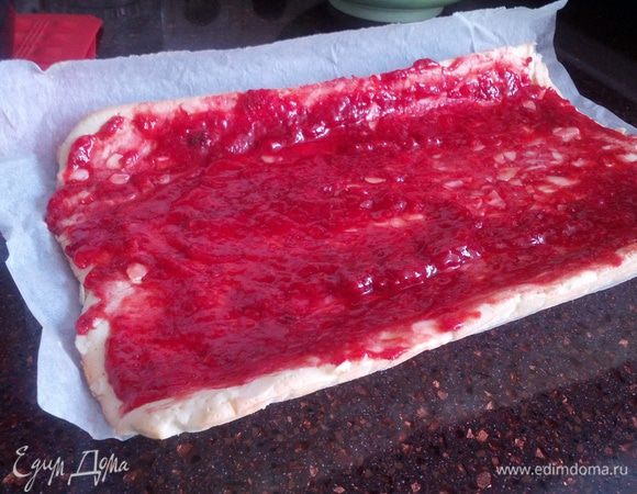 Когда корж остыл, разворачиваем его аккуратно и смазываем джемом полностью. (У меня клубничное варенье - домашняя клубника перемешанная с сахаром и замороженная на зиму, не вареное). 
Кремом смазываем только 2/3 коржа, так как крем еще будет перемещаться вперед, когда его будем закручивать.
