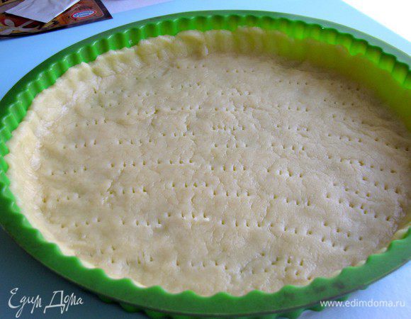 Взять низкую круглую форму диаметром 24 см. Тонко раскатать тесто на столе, стараясь использовать как можно меньше муки. При помощи скалки перенести тесто в форму и прижать к стенкам, формируя бортики. Проткнуть тесто вилкой и поместить в холодильник еще на 15 минут. 