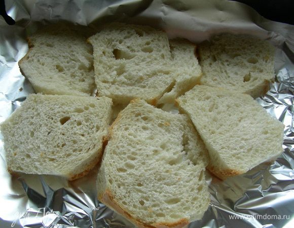 Хлеб режем ломтиками и срезаем корки. Выкладываем его на противень, застеленный бумагой для выпечки.
