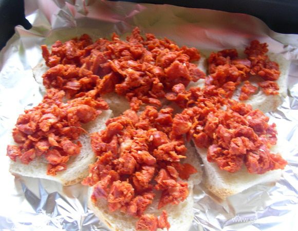 У чоризо снимаем кожуру и мелко ее рубим. Выкладываем на хлеб. Запекаем в духовке 180 гр 15 минут. Чоризо пропитывает хлеб своими соками и ароматами. Даем остыть.
