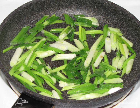 Крупно нарежьте зеленый лук. Поставьте на сильный огонь глубокую сковороду, налейте в нее 1 ст. л. растительного масла. Когда масло разогреется, положите на сковороду зеленый лук и обжаривайте, помешивая, пока лук не станет мягким 3 минуты. Переложите лук на тарелку.
