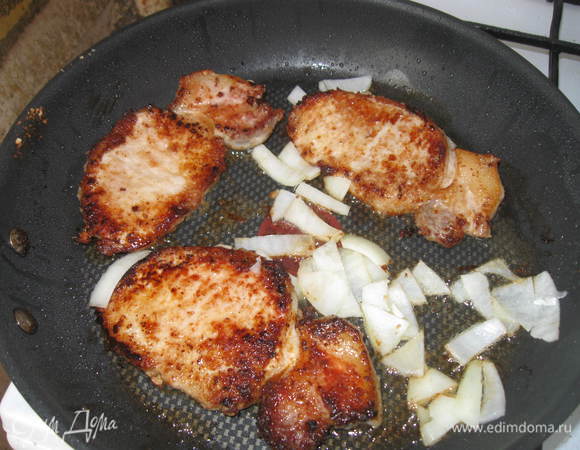 Лук репчатый очистить, порезать. Мясо порезать на куски толщиной 2 см, обвалять в сухарях, поместить на разогретую сковороду.Через 5 мин. поместить туда же лук. Обжаривать с каждой стороны по 5-7 мин.