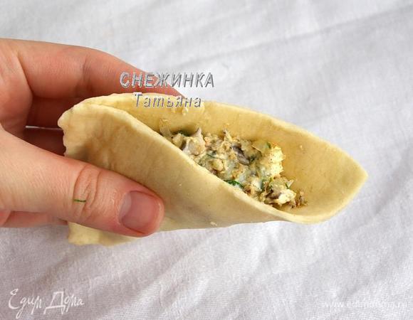 Слоёное тесто раскатываем в виде прямоугольника тонко, от этого зависит скорость выпекания пирожков в духовке. Делим на 6 квадратов. Каждый квадрат теста соединяем уголком, кладём начинку и затем защипываем оставшийся край. Для красоты можно зафиксировать края пирожков вилкой.