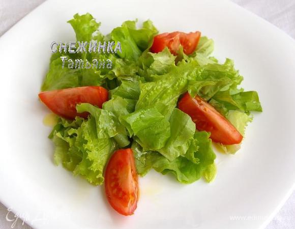 Пока пирожки запекаются, подготовим основу для салата. На порционную тарелку кладём салатные листья. Если салат крупный, рвём его руками. Половинку помидора нарезаем дольками. Сбрызгиваем основу оливковым маслом.