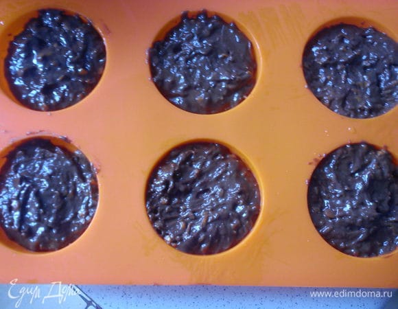 Смазать формы для кексов подсолнечным маслом и выложить тесто, заполняя их на  2/3. Выпекать в заранее разогретой до 180 С духовке 30 минут