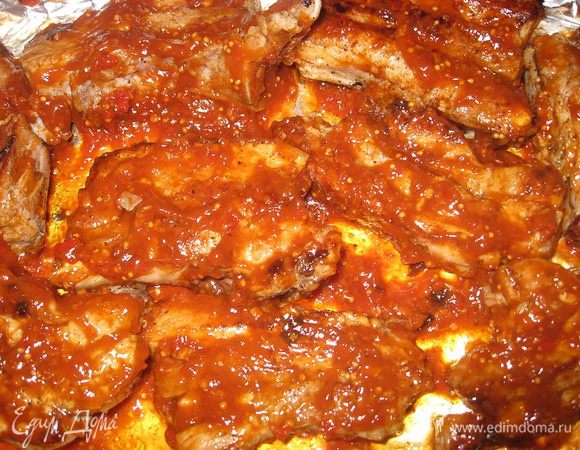Формируем на противне форму из фольги, выкладываем на неё мясо, обильно смазываем с двух сторон соусом. Помещаем противень в разогретую духовку (220 градусов) и запекаем 10-15 минут. Убавляем огонь до 180 градусов и продолжаем запекать 20-25 минут.  