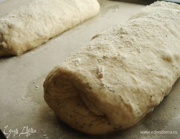 Разделить тесто пополам. Каждый кусок немного размять и свернуть в рулет. Противень застелить пекарской бумагой, присыпать мукой. Хлеб выложить на противень, присыпать сверху мукой и накрыть полотенцем. Оставить хлеб подниматься на 30-45 минут. На хорошо поднявшемся хлебе острым лезвием можно сделать продольный надрез.