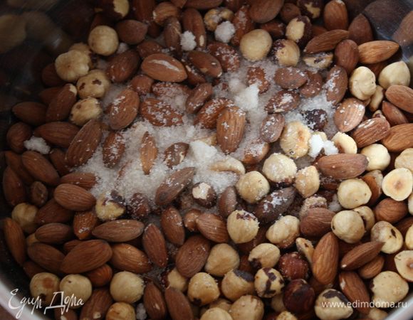 Приступим к ореховой пасте. Орехи можно не чистить, это повлияет только на цвет пасты. Сначала орехи нужно подсушить в духовке, разогретой до 200 градусов примерно 
8-10 минут. Орехи выкладываем на пергамент. Потом складываем орехи в кастрюлю с толстым дном и 
ставим на огонь.