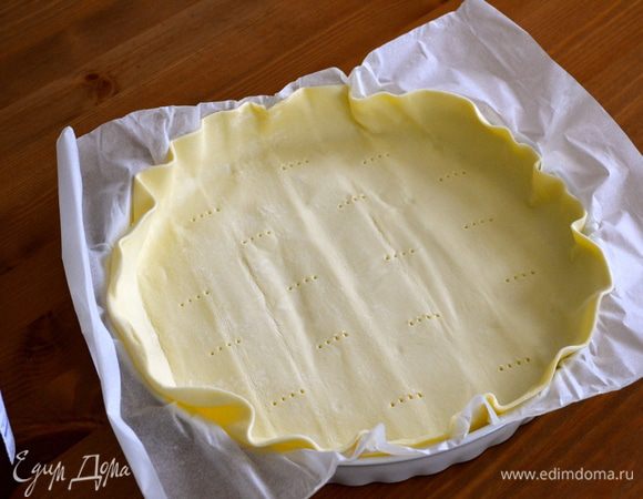 Выложить готовое слоеное тесто (вместе с бумагой) в форму, сформировать бортик и наколотить вилкой, чтобы тесто не вздулось при выпечки. 