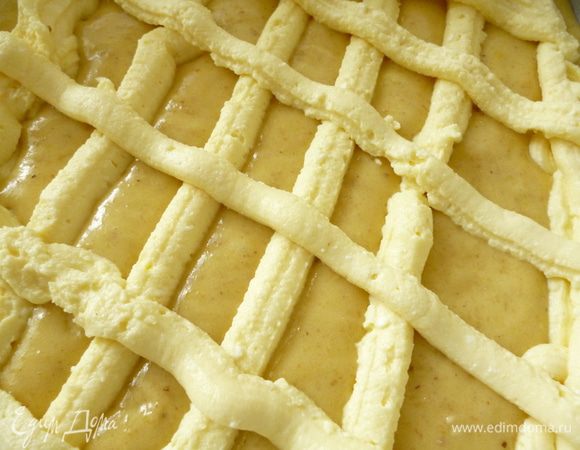 Форму для выпечки застелить пергаментом, смазать пергамент маргарином и подпылить манкой. Распределить тесто. Затем с помощью кондитерского шприца или самодельного кулечка из пергамента нанести кремовые полоски в виде сетки. У меня случилась авария, порвался пакетик и некоторые полоски получились не очень красивые. Нижние полоски я накладывала в два слоя. Выпекать пирог при 170-180 градусах 35-40 минут, до сухой спички.