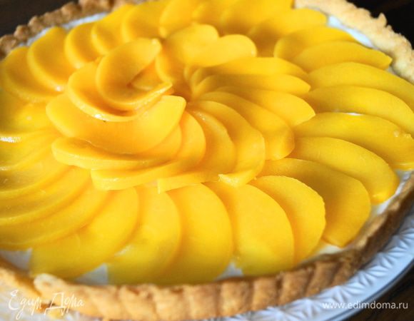 Персики нарезать тоненькими пластинками и выложить их на тарт по кругу