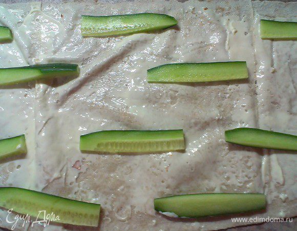 Режем огурец пополам и затем соломкой, раскладываем на намазанный лаваш в шахматном порядке, негусто  