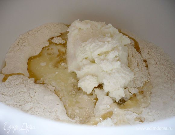 Замешиваем тесто для основы. Муку смешиваем с разрыхлителем и солью, добавляем творог, масло и молоко и сахар. Вымешиваем до однородности, подливая воду, пока тесто не приобретет эластичность.