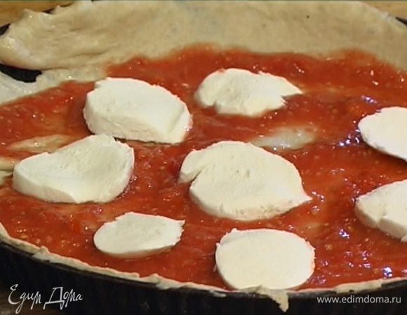Круглую форму для выпечки смазать оливковым маслом, уложить в нее тесто, равномерно смазать пласт томатной массой, сверху разложить моцареллу.