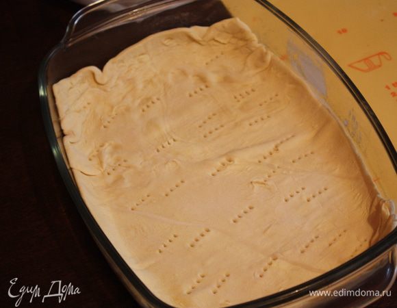 Теперь тесто. Нам нужно 2 одинаковые части.Одну часть мы раскатываем под размер формы. Форму смазываем раст. маслом и присыпаем мукой. Выкладываем тесто в форму, оставляя бортики открытыми. Сверху на пергамент высыпаем сухой горох (или фасоль) и отправляем  в разогретую до 200 градусов духовку на 20 минут.