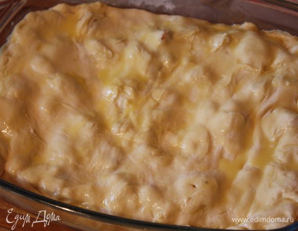 Второй пласт теста раскатываем (я не очень люблю в таких пирогах, когда тесто сильно поднимается, поэтому немного мну тесто, а потом начинаю раскатывать) чуть больше, накрываем нашу начинку. Подворачиваем края,смазываем желтком, разведенным водой и отправляем в духовку 
при 180 градусах на 35-40 минут.