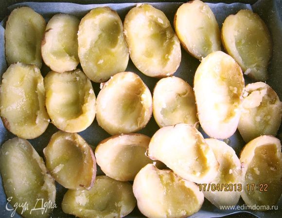 Разрезаем картофель вдоль на половинки и чайной ложкой делаем углубления (не больше косточки авокадо). Выстилаем противень пергаментом и складываем половинки, взбрызгиваем оливковым маслом.
