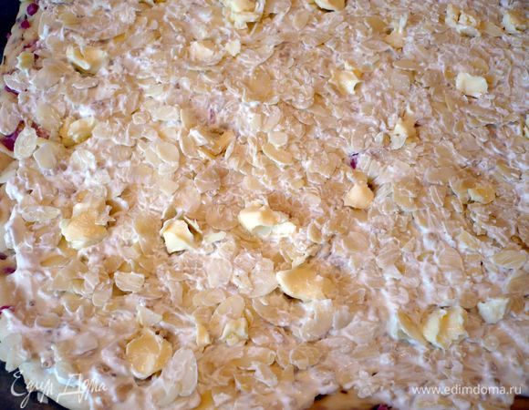 Разогреваем духовку до 180 градусов. Слегка рубим кедровые орехи, смешиваем со сметаной, добавляем молотый перец и распределяем по подошедшему тесту, выкладывая сверху лепестки миндаля, так чтобы и миндаль был немного покрыт сметанно-кедровой массой. В тесте делаем пальцем углубления и выкладываем в них небольшие кусочки оставшегося сливочного масла. Посыпаем морской солью. Ставим в духовку на полчаса.