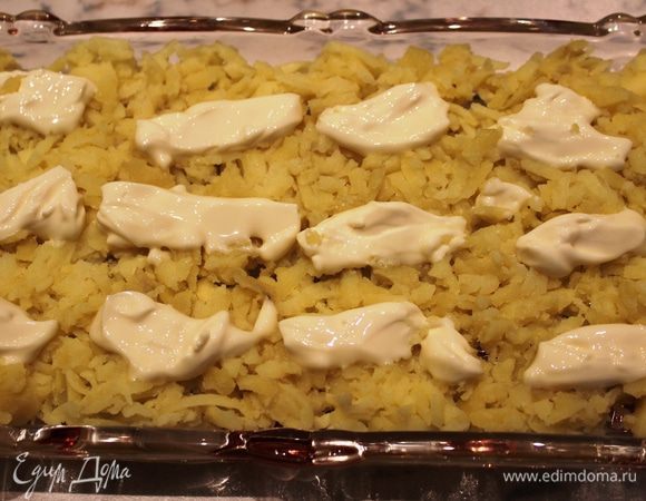 Первый слой - картофель, натертый на терке. Поверх картофеля разложить небольшими порциями мягкий сливочный сыр (6 ст.л.)