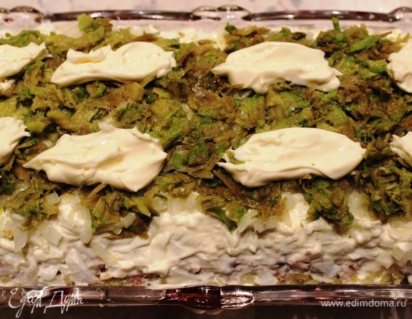 Четвертый слой - авокадо...его необходимо очистить, натереть на терке и смочить лимонным соком. Поверх авокадо разложить небольшими порциями мягкий сливочный сыр (4 ст.л.)