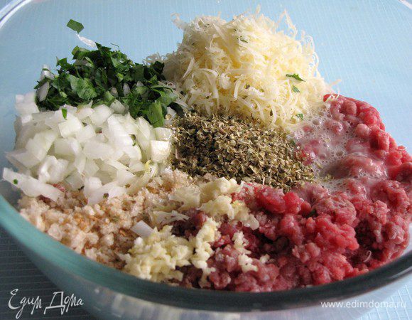 Измельчить лук и петрушку, чеснок пропустить через пресс, легко взбить яйцо. Соединить в миске мясной фарш, лук, чеснок, петрушку, хлебные крошки, пармезан, орегано и яйцо. Послолить, поперчить.