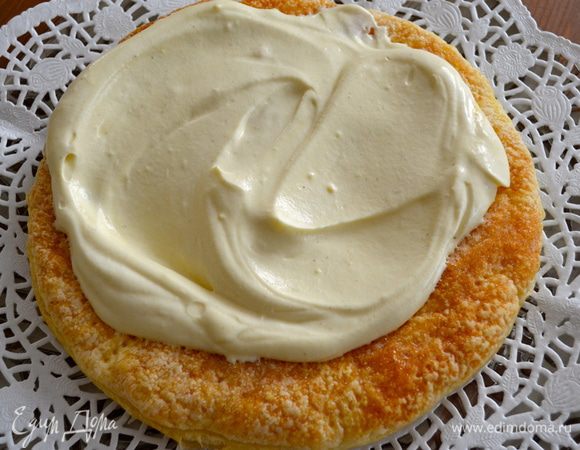 Теперь можно приступать к сборке торта. На блюдо выложить первый корж из слоеного теста, и смазать его половиной крема. 