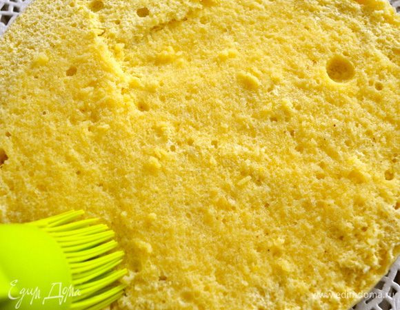 Сверху положить бисквит и пропитать его обильно сахарным сиропом с ромом. (или персиковым соком) 