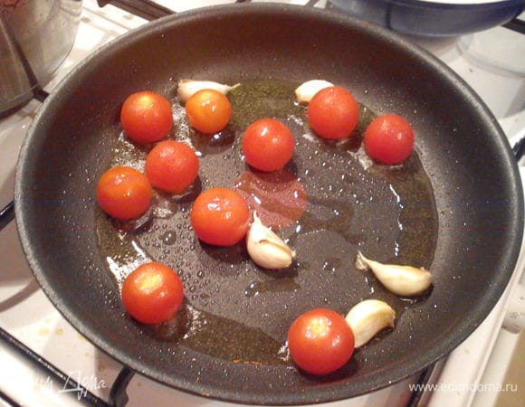 Неочищенные зубчики чеснока наколоть ножом и обжарить в разогретом масле 2-3 минуты. Добавить помидоры и обжарить до мягкости.
