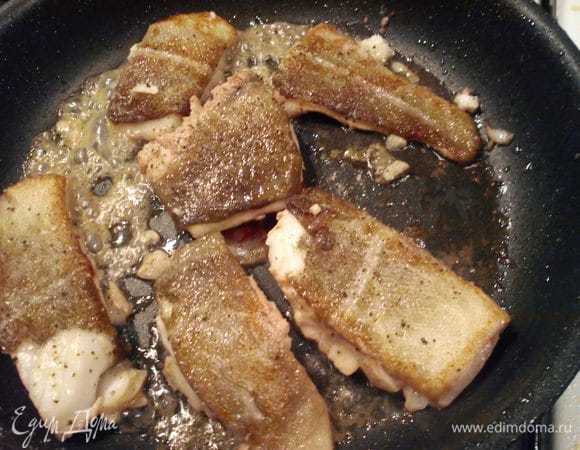 Выложить помидоры и чеснок на тарелку, а рыбку обжарить в том же чесночном масле до румяной корочки. Перевернуть 1 раз. Приправить солью, перцем и специями для рыбы.