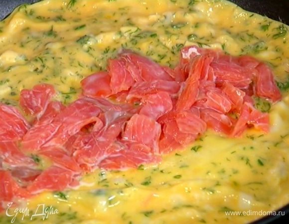 Когда омлет будет практически готов, в центр выложить форель и с помощью лопаток завернуть на рыбу сначала один край омлета, затем второй.