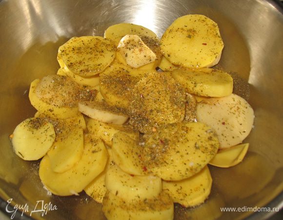 Складываем картофель в емкость, поливаем растительным маслом, добавляем соль, черный перец и специи. Хорошо перемешиваем руками, следя за тем чтобы каждый ломтик был покрыт маслом.   
