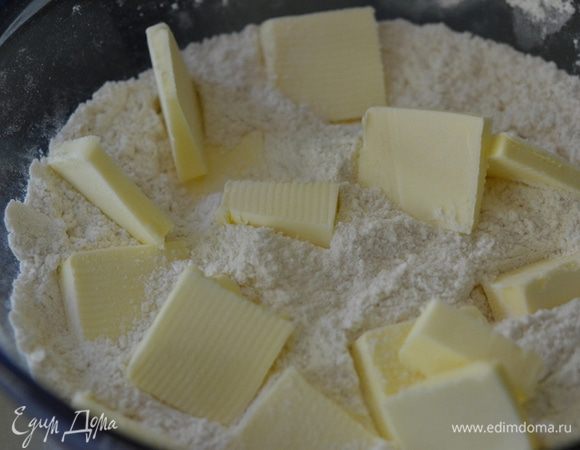 Приготовим бисквит. Смешаем муку и сахар. Добавим холодное сливочное масло порезанное на кусочки. Порежем все в месте в крошку ножом или вилкой. Отложим 3/4 стакана в сторону. В эту часть добавим разрыхлитель, пищевую соду и соль. Перемешаем.