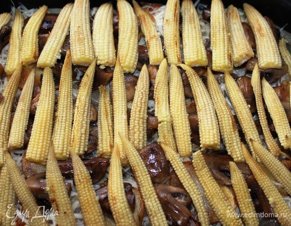 Следующий слой - кукуруза. Ее необходимо поджарить в масле, нарезать пополам вдоль и разложить поверх грибов