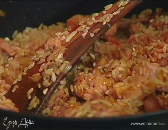 Выложить кусочки кролика к луку с беконом, увеличить огонь, добавить печень кролика, томатную пасту, копченую паприку, влить шафран с бульоном, перемешать, затем всыпать рис и посолить.