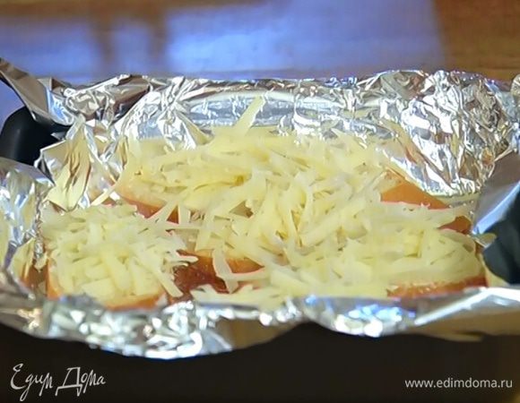 Хлеб нарезать, каждый кусок с одной стороны намазать оставшимся сливочным маслом, выложить маслом вверх в выстеленный фольгой противень и посыпать сыром. Отправить хлеб на 2–3 минуты под разогретый гриль.