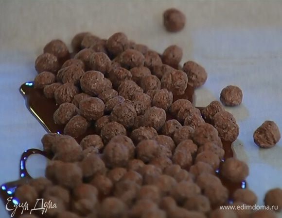 Расстелить на рабочей поверхности бумагу для выпечки, вылить на середину часть растопленного черного шоколада, насыпать на него шоколадные шарики и залить оставшимся черным шоколадом. Накрыть краями бумаги, постучать сверху толкушкой, чтобы немного раздробить шарики, и отправить шоколадную массу на 5 минут в морозильник.