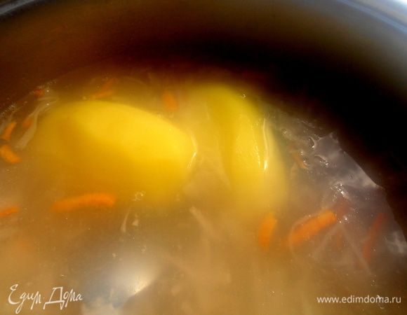 Отправляем всю капусту со специями в бульон и туда же целиком я кладу картофель...