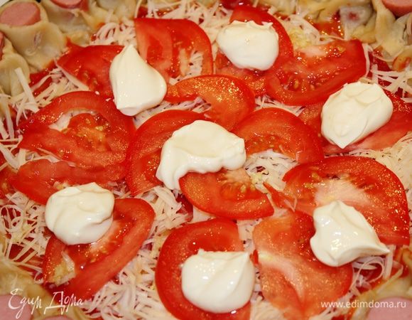 Помидор нарезать на тонкие пластинки и разложить их на поверхности пиццы. Поверх него выложить мягкий сливочный сыр небольшими порциями