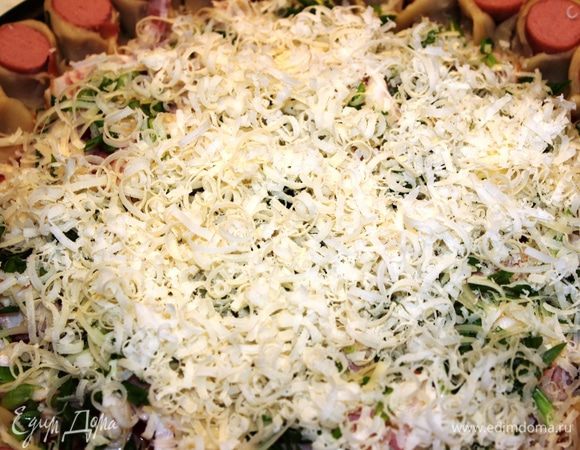 Оставшуюся часть сыра натереть и посыпать всю поверхность пиццы (по центру)